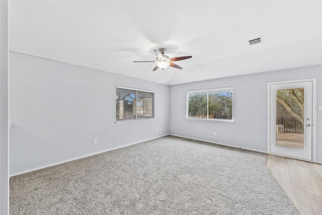 carpeted spare room featuring visible vents, baseboards, and a ceiling fan