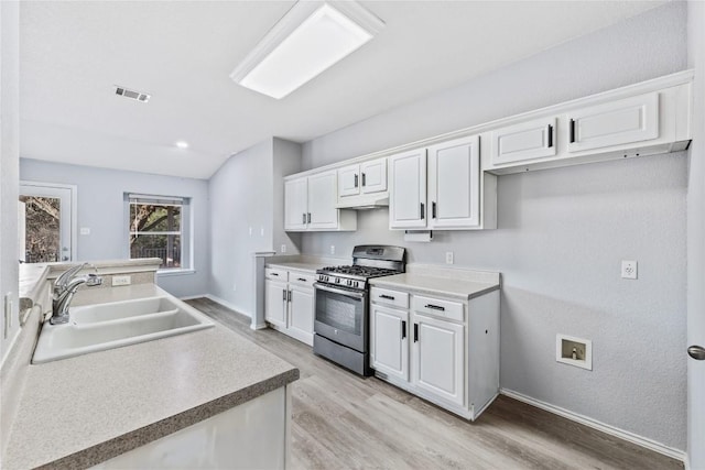 kitchen with gas stove, visible vents, a sink, white cabinets, and under cabinet range hood