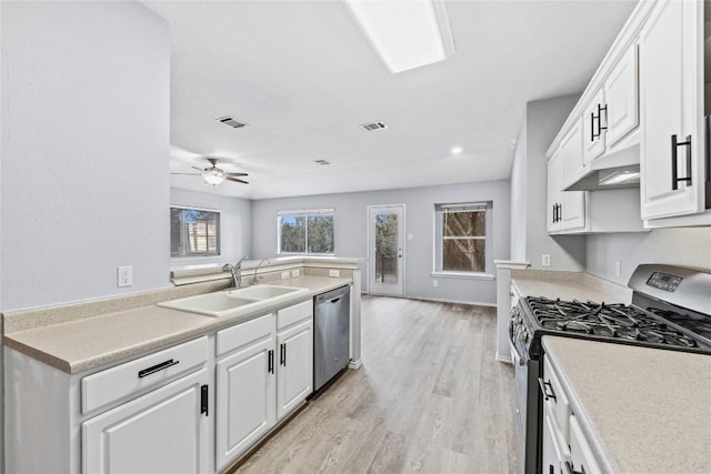 kitchen featuring visible vents, a sink, under cabinet range hood, stainless steel appliances, and light wood-style floors