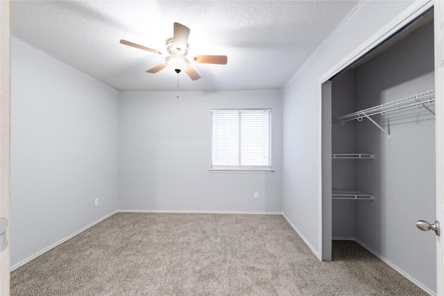 unfurnished bedroom featuring baseboards, ceiling fan, carpet, a closet, and a textured ceiling