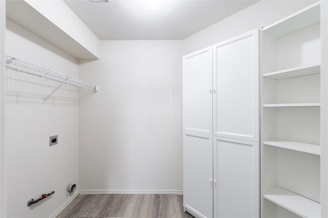 laundry room featuring wood finished floors, hookup for an electric dryer, gas dryer hookup, cabinet space, and a textured ceiling