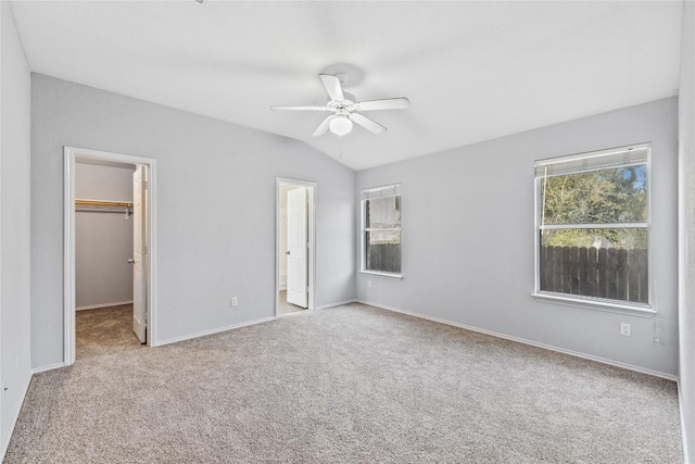 unfurnished bedroom with a ceiling fan, carpet floors, vaulted ceiling, a spacious closet, and a closet