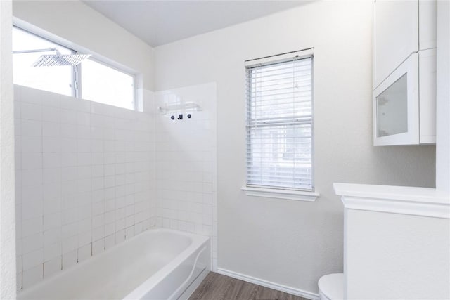 bathroom with baseboards, toilet, bathtub / shower combination, and wood finished floors