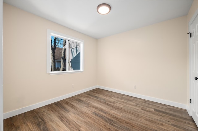 empty room featuring dark wood-style floors and baseboards