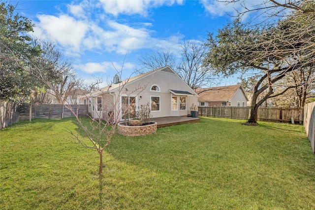 rear view of house with central AC unit, a lawn, and a fenced backyard