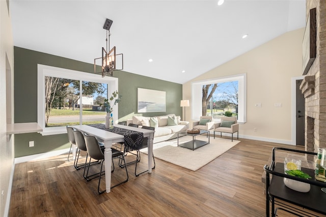 dining space with baseboards, an inviting chandelier, wood finished floors, and vaulted ceiling