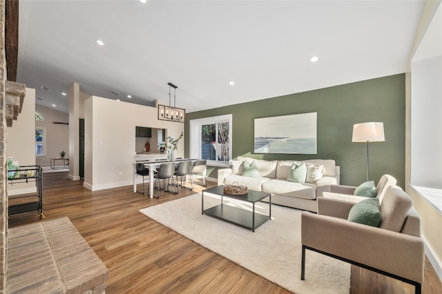 living room with baseboards, lofted ceiling, recessed lighting, an inviting chandelier, and wood finished floors