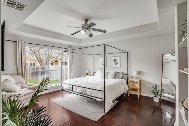 bedroom featuring a raised ceiling, wood finished floors, and visible vents