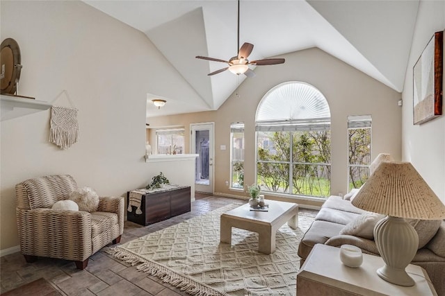 living room with plenty of natural light, high vaulted ceiling, ceiling fan, and stone finish floor