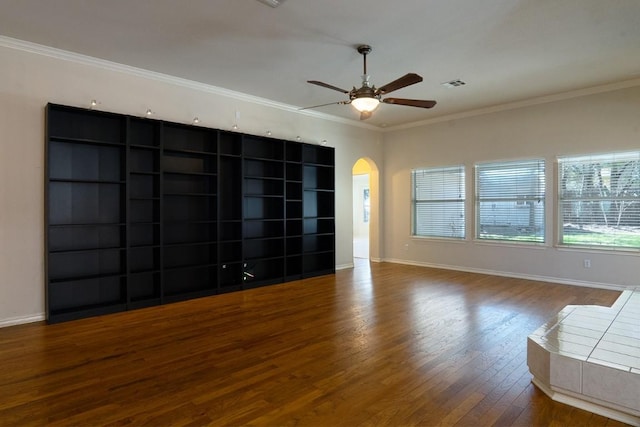 unfurnished living room featuring baseboards, wood finished floors, arched walkways, and ornamental molding