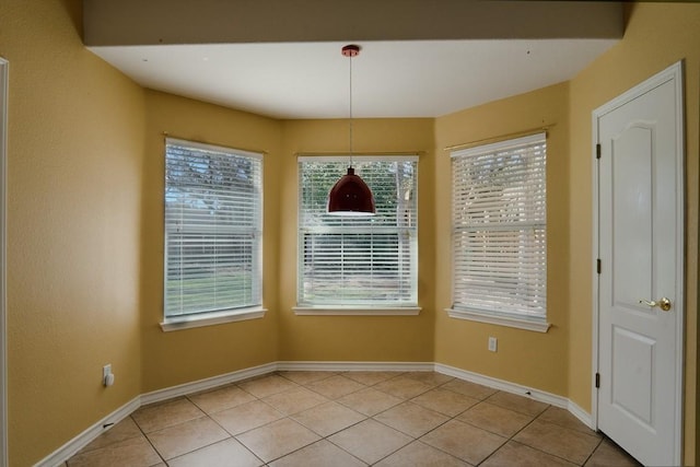 unfurnished dining area with light tile patterned flooring, baseboards, and a wealth of natural light