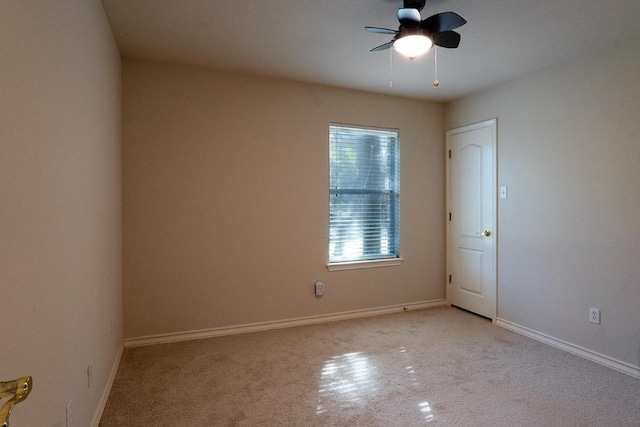 unfurnished room with light colored carpet, baseboards, and a ceiling fan