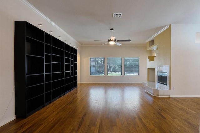 unfurnished living room featuring visible vents, a tiled fireplace, wood finished floors, crown molding, and baseboards