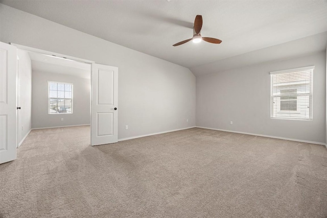 carpeted spare room with ceiling fan, baseboards, and vaulted ceiling