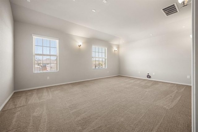 carpeted spare room featuring baseboards and visible vents