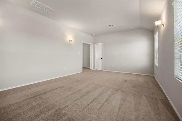 carpeted spare room featuring visible vents, baseboards, and lofted ceiling