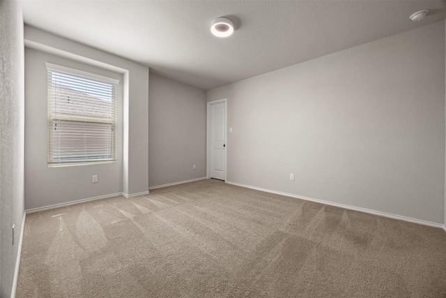 carpeted spare room featuring baseboards