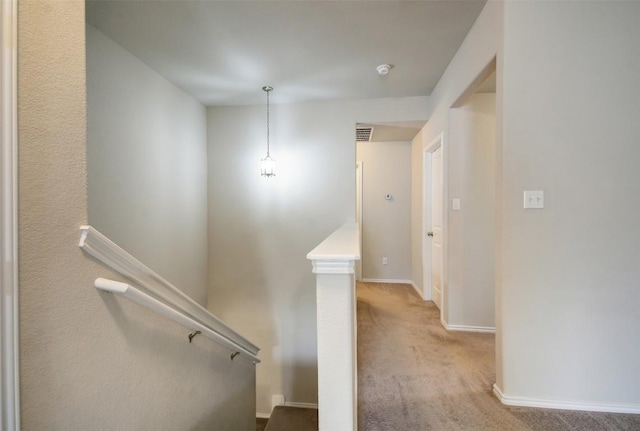 hallway with visible vents, carpet floors, baseboards, and an upstairs landing