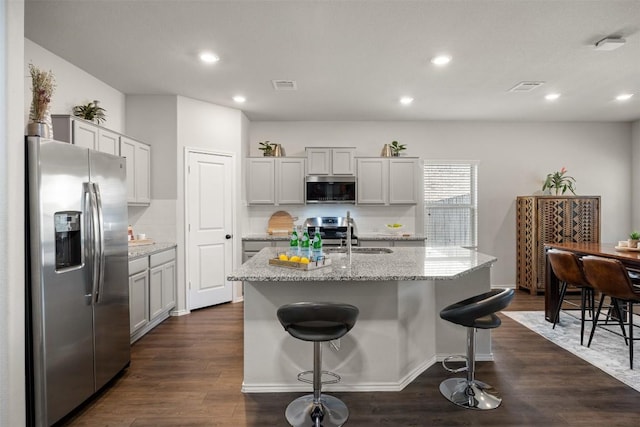 kitchen with a sink, dark wood-style floors, visible vents, and stainless steel appliances