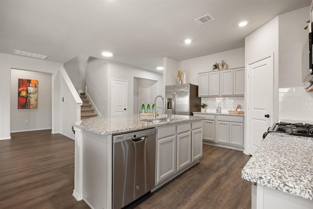 kitchen with visible vents, a kitchen island with sink, a sink, dark wood-style floors, and stainless steel appliances