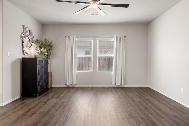 spare room featuring baseboards, a ceiling fan, and dark wood-style flooring