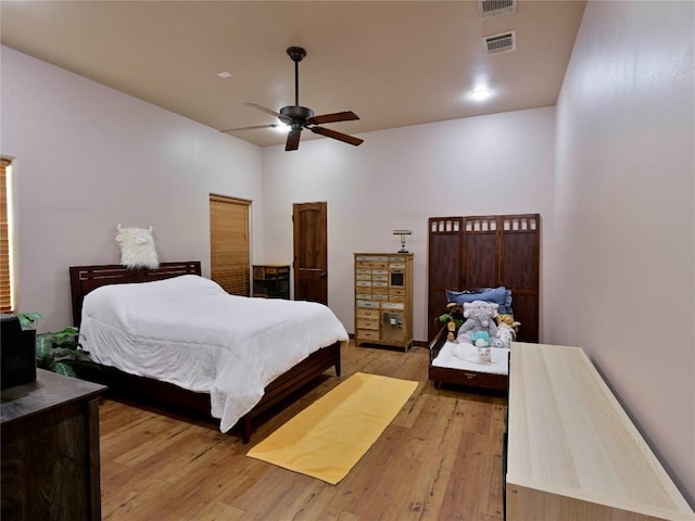 bedroom with light wood finished floors, visible vents, and a ceiling fan