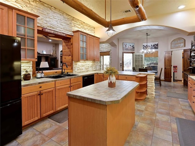 kitchen featuring black appliances, a peninsula, arched walkways, and a sink