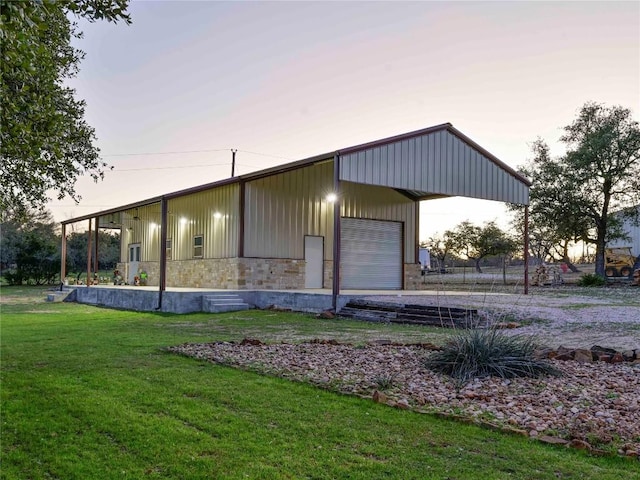 outdoor structure at dusk featuring an outdoor structure, a lawn, and driveway