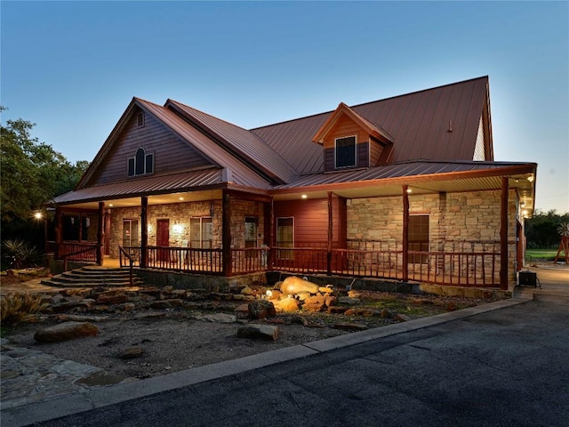 view of front of house with stone siding, a porch, and metal roof