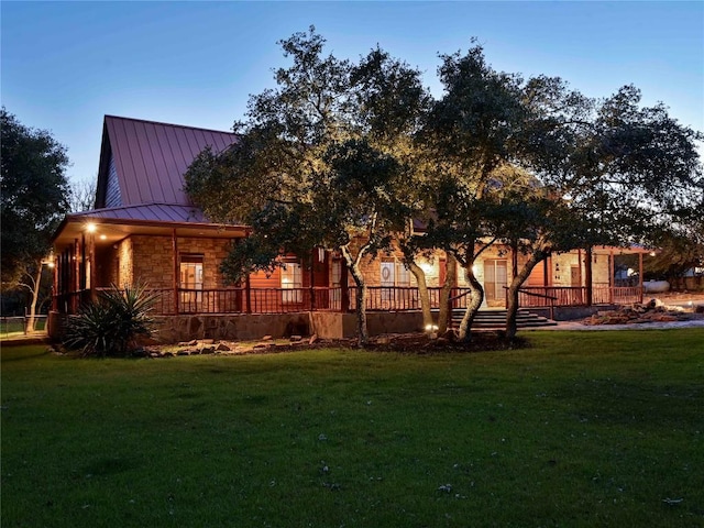 view of side of home with stone siding, a lawn, metal roof, and a standing seam roof