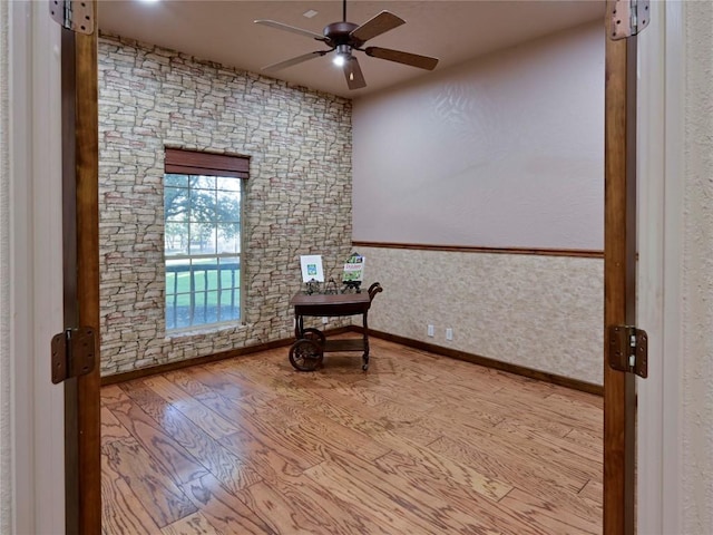 unfurnished room with wood finished floors, baseboards, and ceiling fan