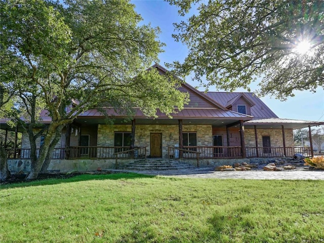 country-style home featuring a front lawn, a porch, metal roof, stone siding, and a standing seam roof