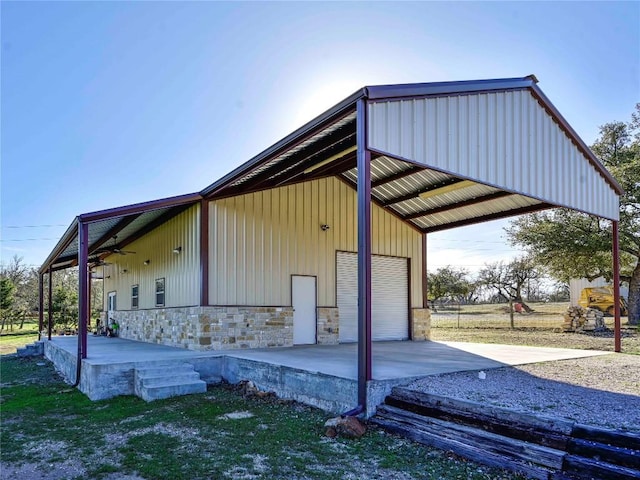 view of outdoor structure with a carport, driveway, and an outbuilding