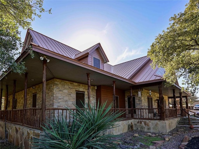 view of front of home with metal roof, stone siding, and a porch