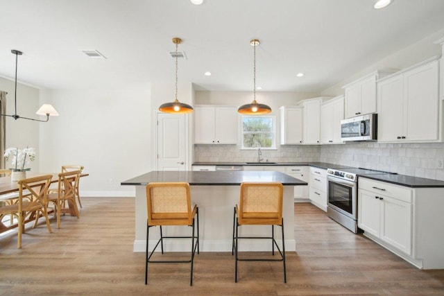 103 Manana Ct, Bastrop, TX 78602 - kitchen with appliances with stainless steel finishes, dark countertops, white cabinets, recessed lighting, and light wood-type flooring