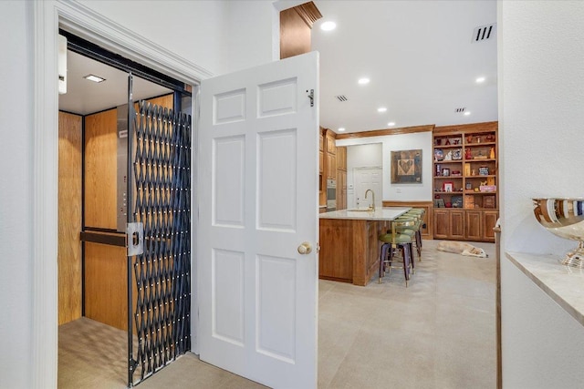 interior space featuring visible vents, a breakfast bar, a sink, built in features, and recessed lighting