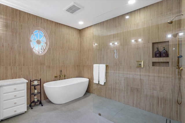 bathroom with tile patterned flooring, visible vents, walk in shower, and a freestanding tub