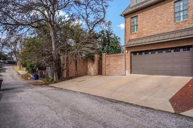 view of home's exterior featuring brick siding, concrete driveway, an attached garage, and a standing seam roof