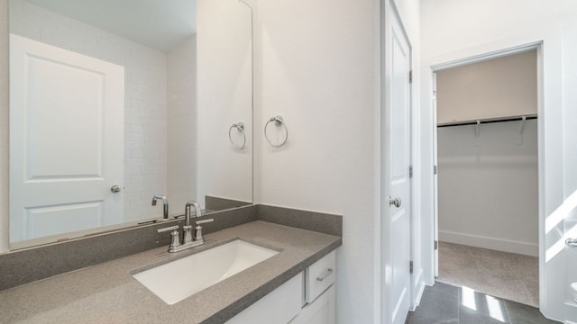 bathroom with a walk in closet and vanity