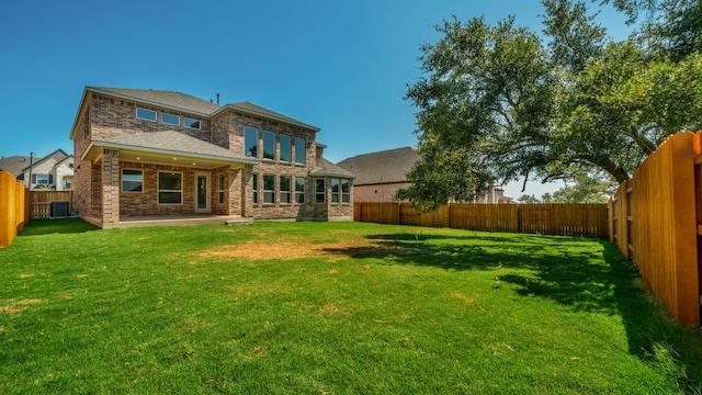 back of property with a patio, a lawn, brick siding, and a fenced backyard