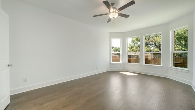 empty room with baseboards, a ceiling fan, and dark wood-style flooring