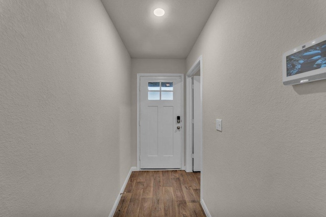 entryway featuring baseboards, dark wood-style flooring, and a textured wall