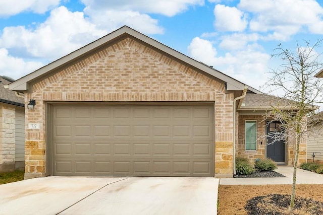 single story home with concrete driveway, brick siding, a garage, and stone siding