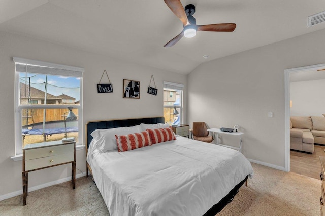 carpeted bedroom with lofted ceiling, multiple windows, baseboards, and visible vents