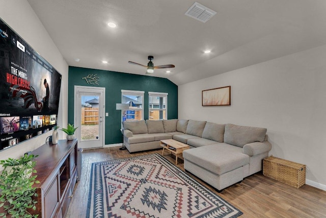 living area with vaulted ceiling, wood finished floors, visible vents, and baseboards