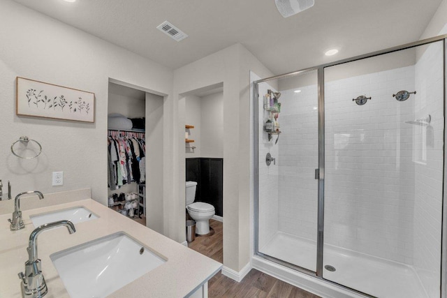 bathroom featuring a sink, visible vents, wood finished floors, and a stall shower