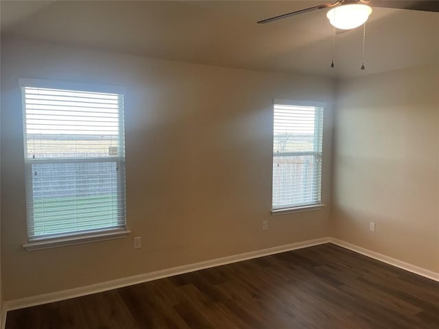 empty room with dark wood finished floors, baseboards, and a ceiling fan