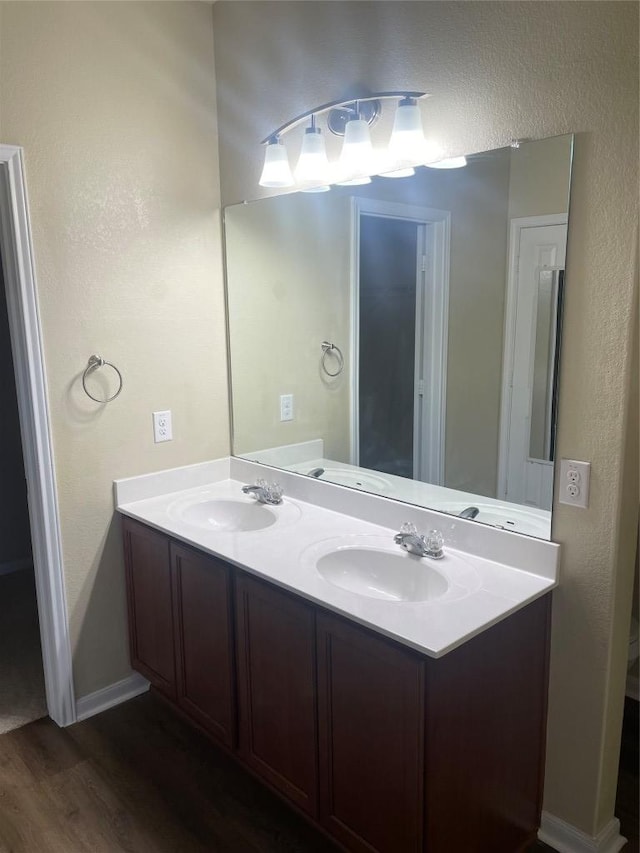 full bath with double vanity, wood finished floors, and a sink