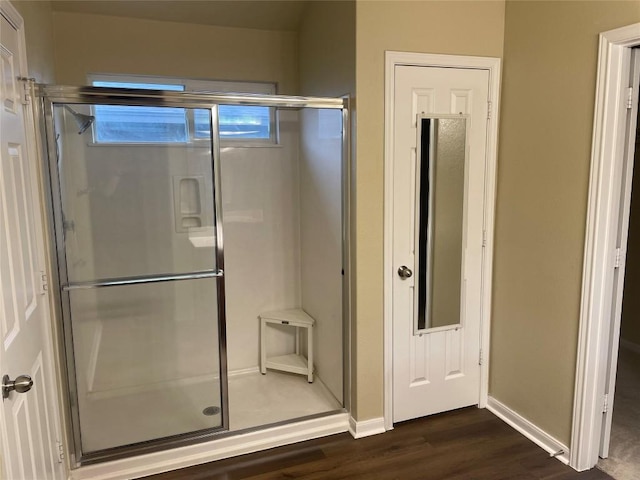 bathroom with a stall shower, baseboards, and wood finished floors