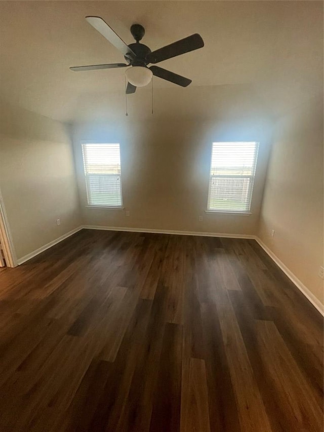 spare room with ceiling fan, baseboards, and dark wood finished floors